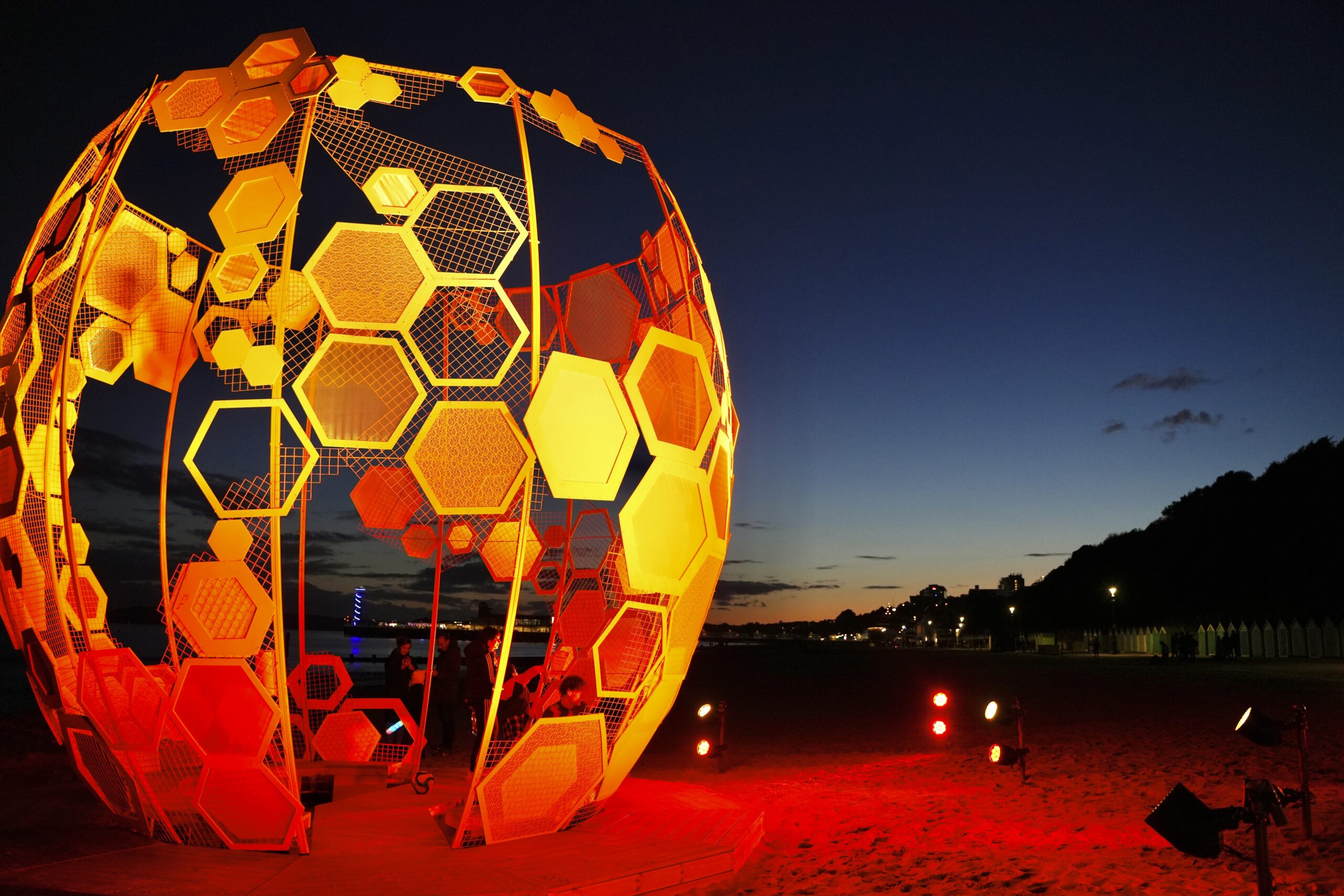 A honeycomb strcture bathed in gold light on the beach in Bournemouth.